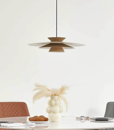 Candeeiro suspenso moderno sobre mesa de jantar com tons naturais quentes e design intemporal.