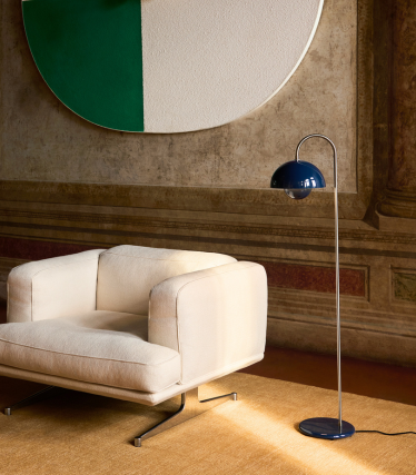 Elegante candeeiro de pé &Tradition ao lado de uma moderna poltrona lounge num interior acolhedor.