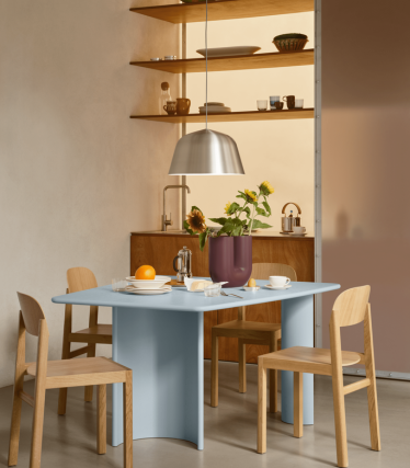 Sala de jantar minimalista com candeeiro suspenso, prateleiras de madeira e mesa posta.
